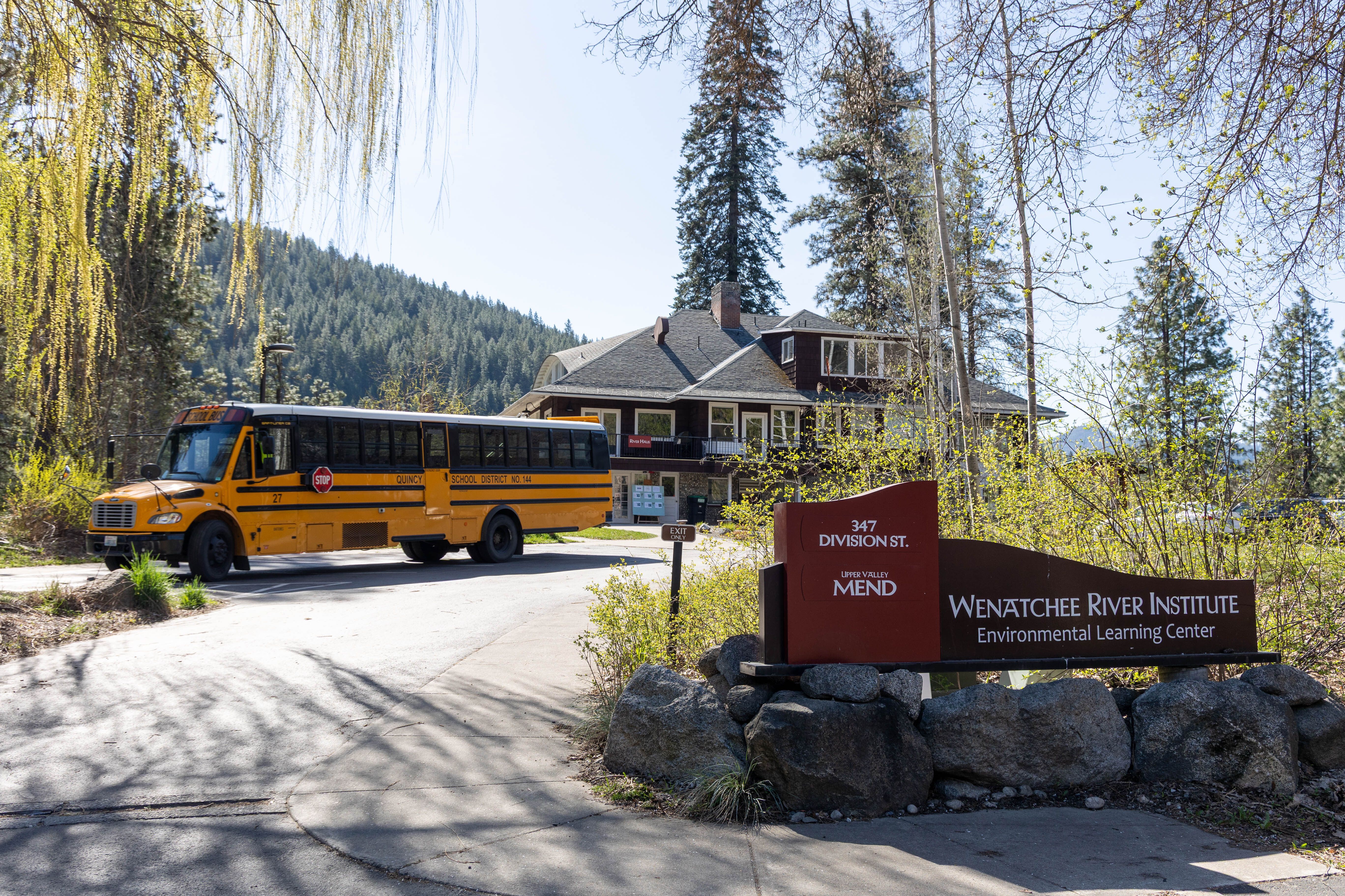 An image of a school bus parking in front of WRI's River Haus with the entrance sign in the forefront.
