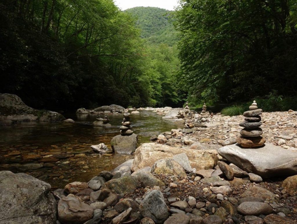 Image of several stacks of rocks on the sides of the river in the mountains