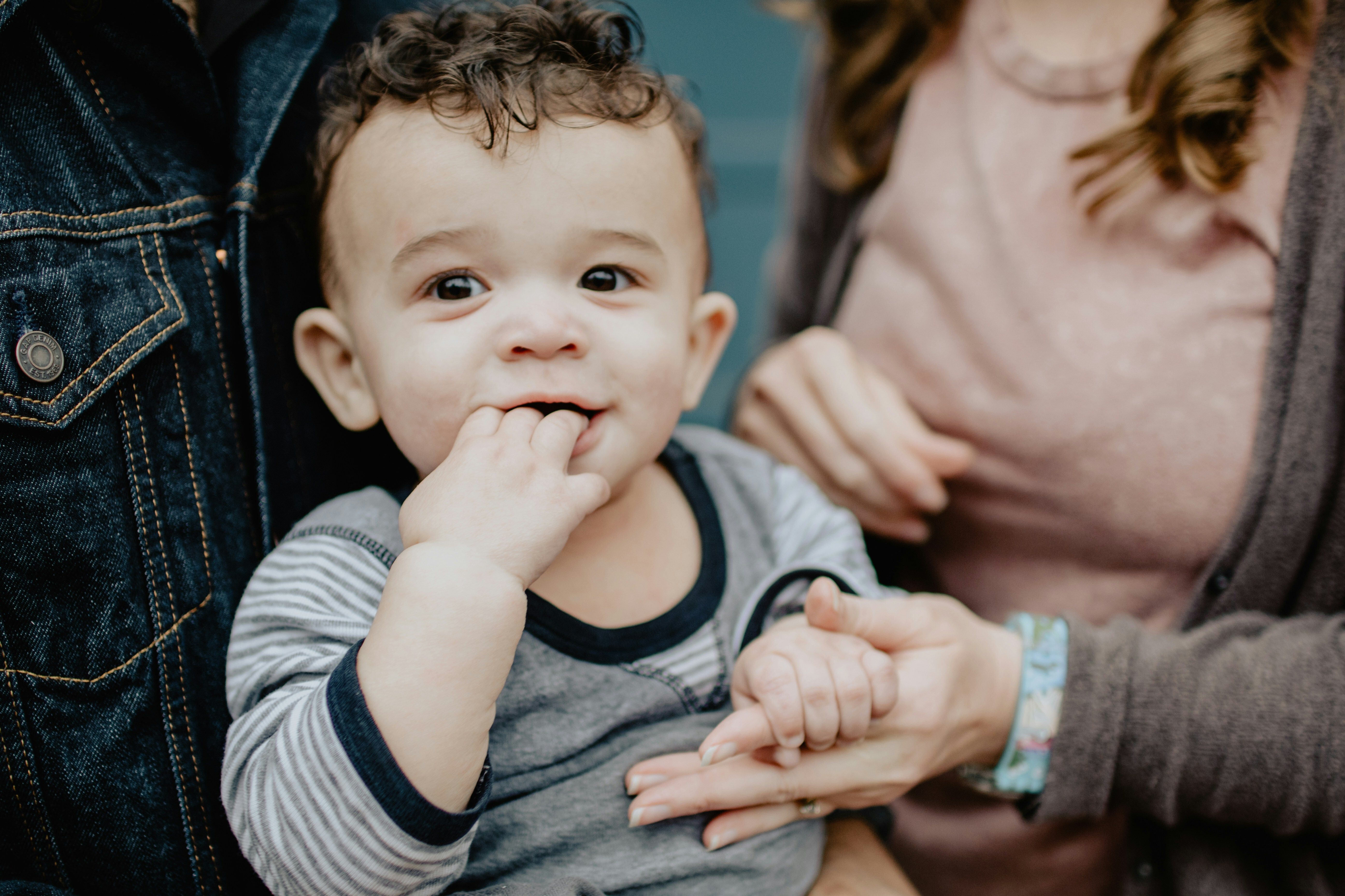 Baby with curly hair and fingers in his mouth