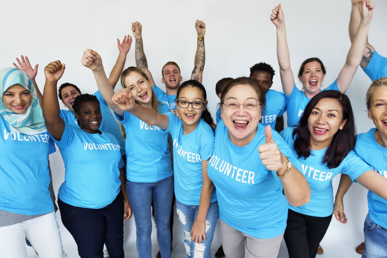 people of different ethnicities cheering wearing a shirt that reads 'volunteer'