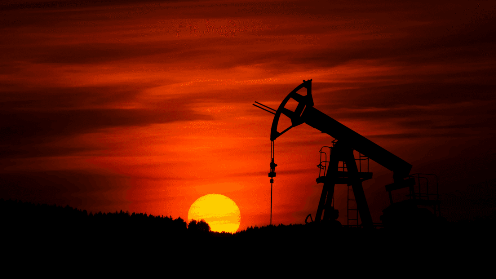 Silhouette of oil well in front of red sunset