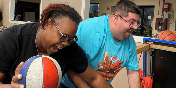 an African American woman and a Latino man with disabilities playing basketball
