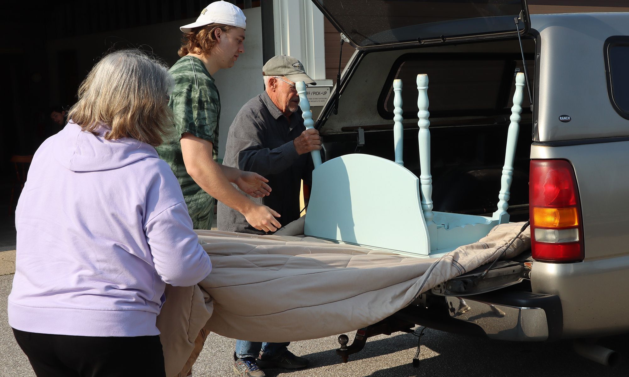 People unload a table from the back of a car.