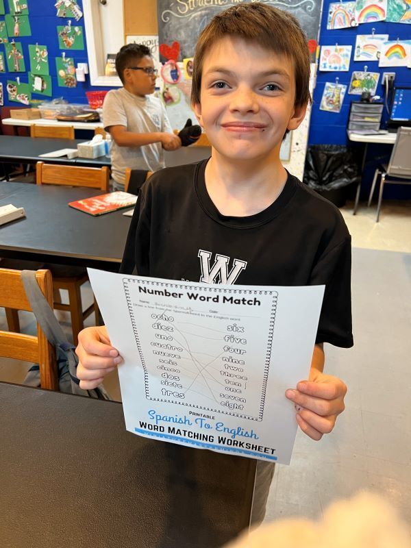 A student from one of Operation Homework's afterschool program proudly displays a worksheet that he completed.  