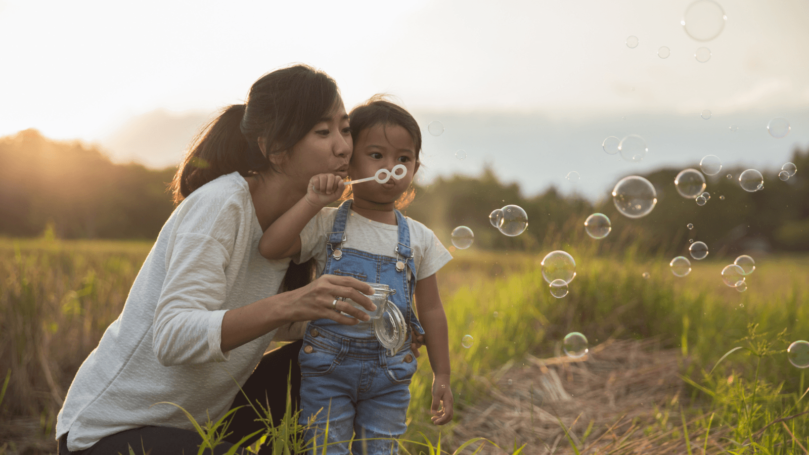 Child and mom blowing bubbles outside