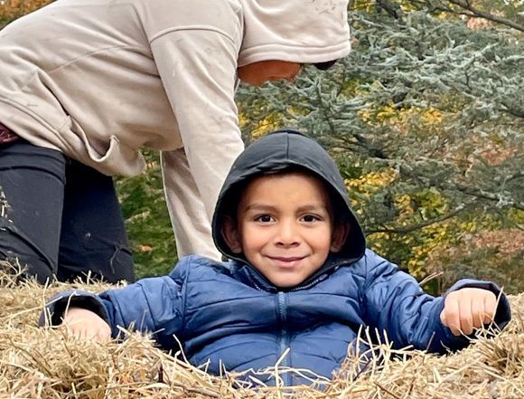 A boy sits atop the Hay Pyramid at Snipes Farm with a giant smile on his face