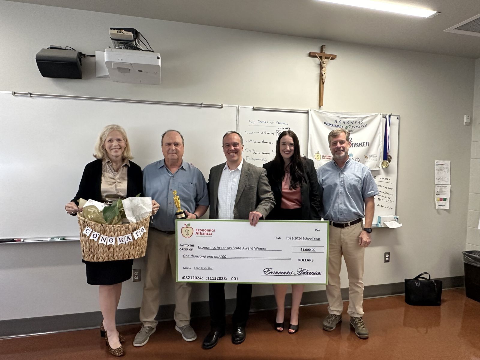 group of adults presenting large check and award to teacher