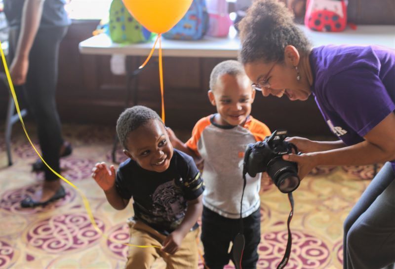 Photographer shows her camera to two boys at the Quality Inn overflow shelter