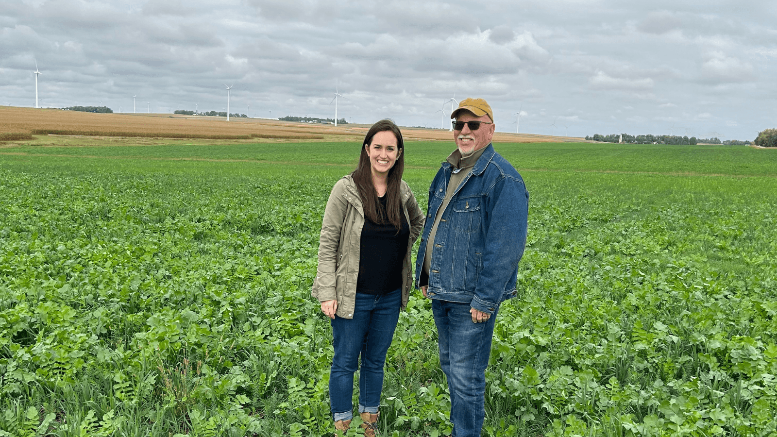 Jessica Moerman and Tim Olsen stand side by side in a green farm field in Minnesota