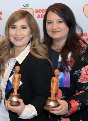 two women smiling and holding awards