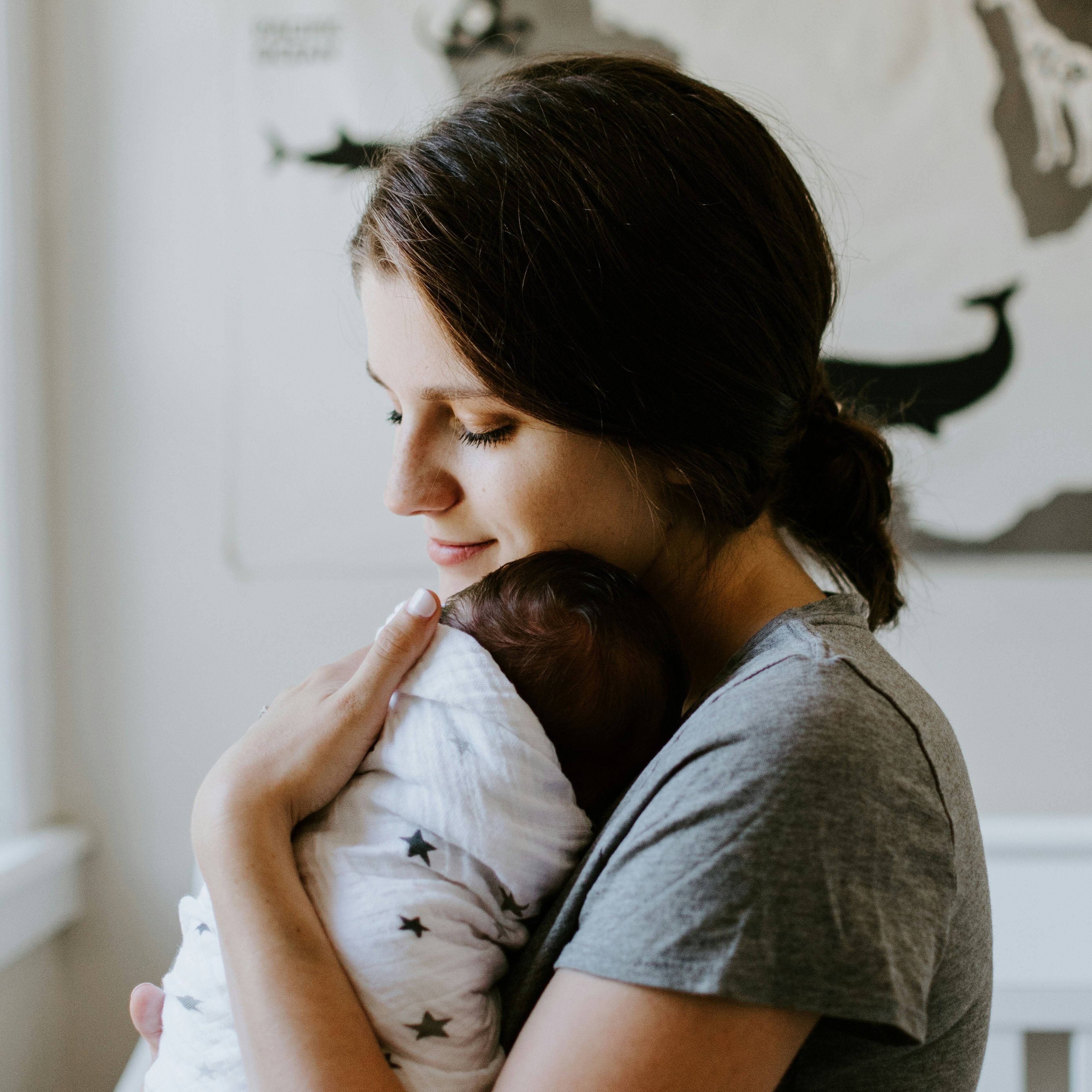 A parent holds a swaddled baby