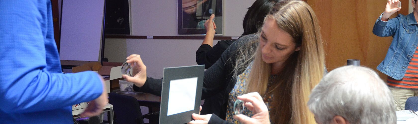 People participating in a hands-on workshop, examining materials with frames and optical objects.