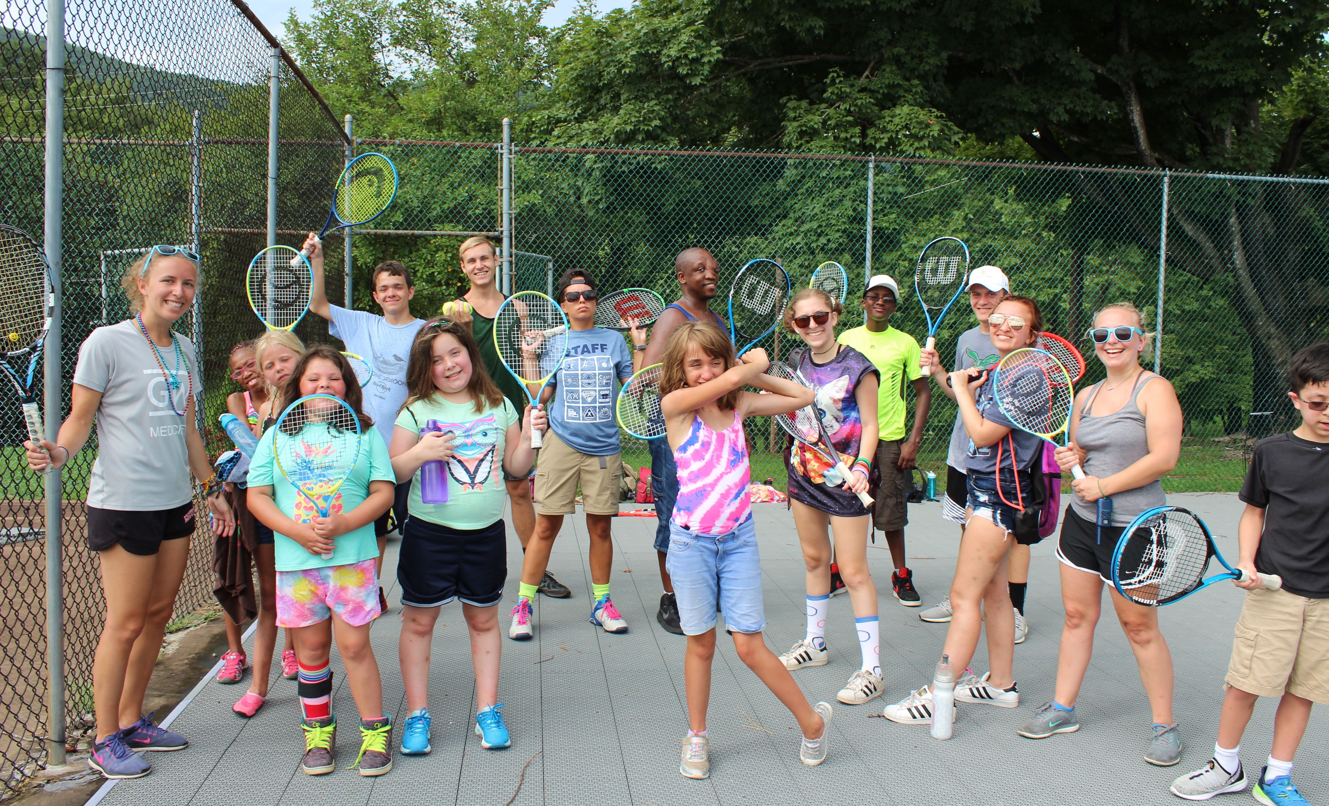 Campers hold tennis rackets and pose for a photo.