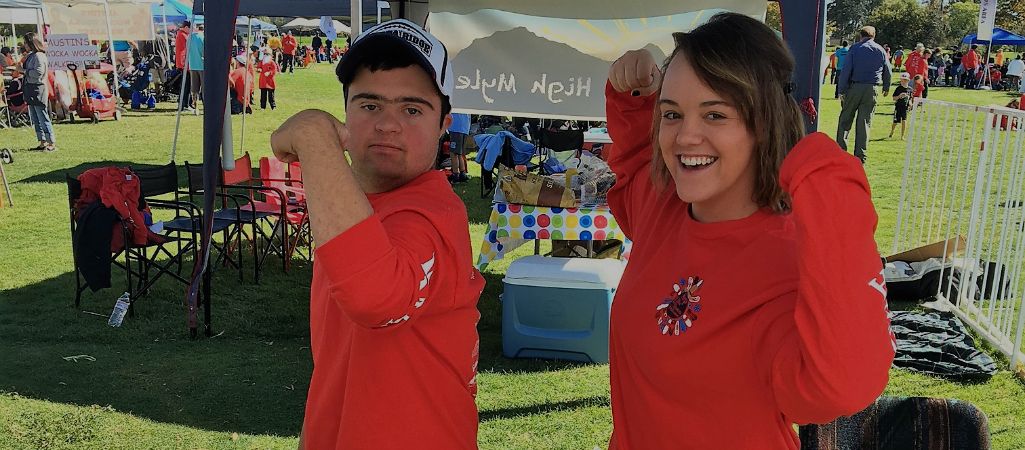 Two young people stand at outdoor booth wearing matching shirts