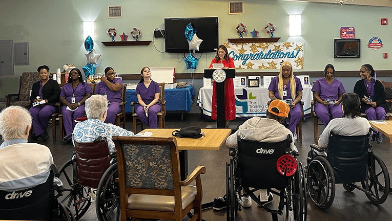Nurse Aide Training Center Director Jenna Klaus addresses the latest graduates of the program. This was the first NATC class referred and enrolled by the Industry Partnership CNA Training Hub.