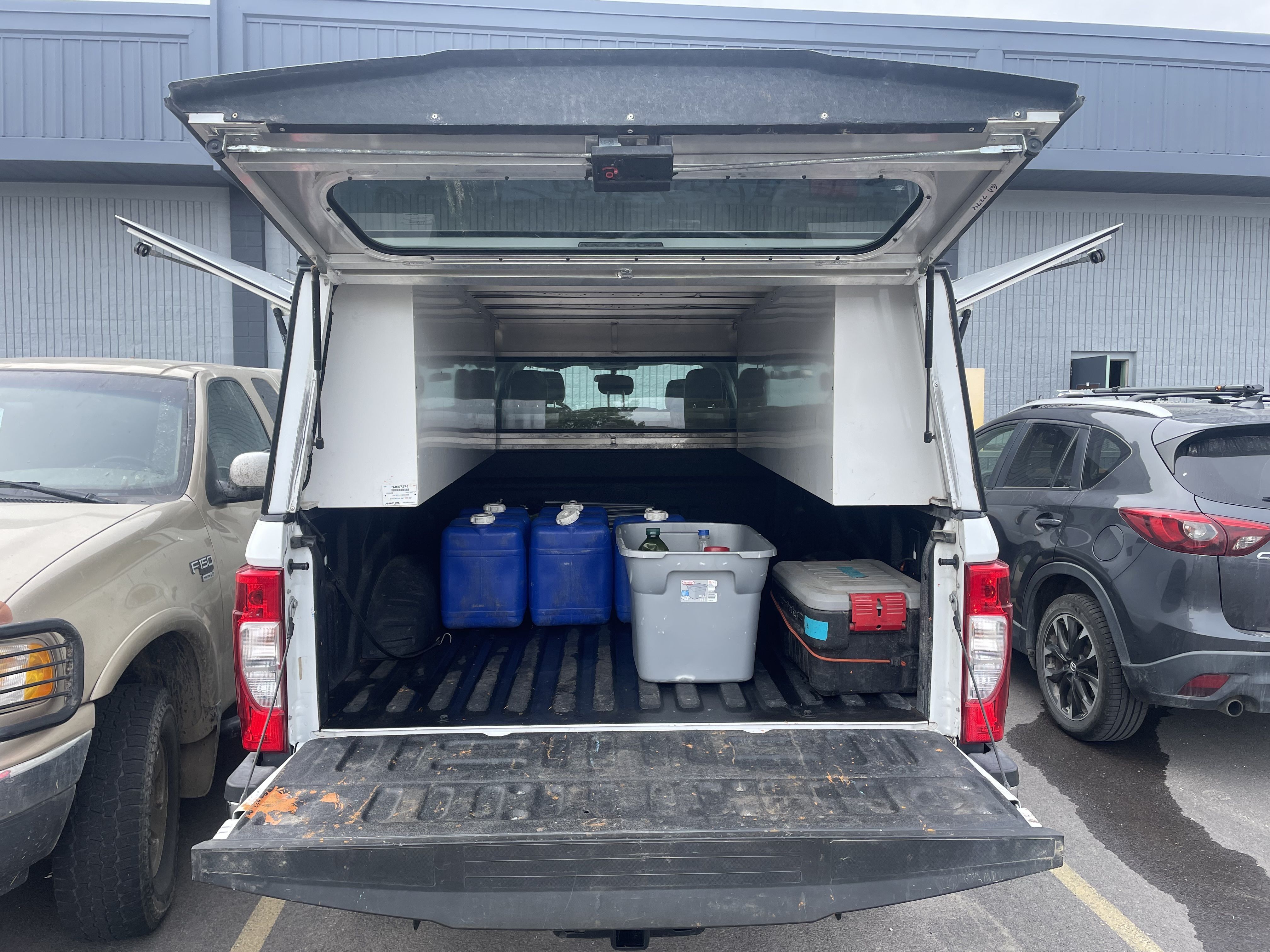 The back of a truck with containers and water jugs.