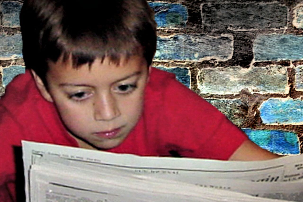 Young boy reading a newspaper