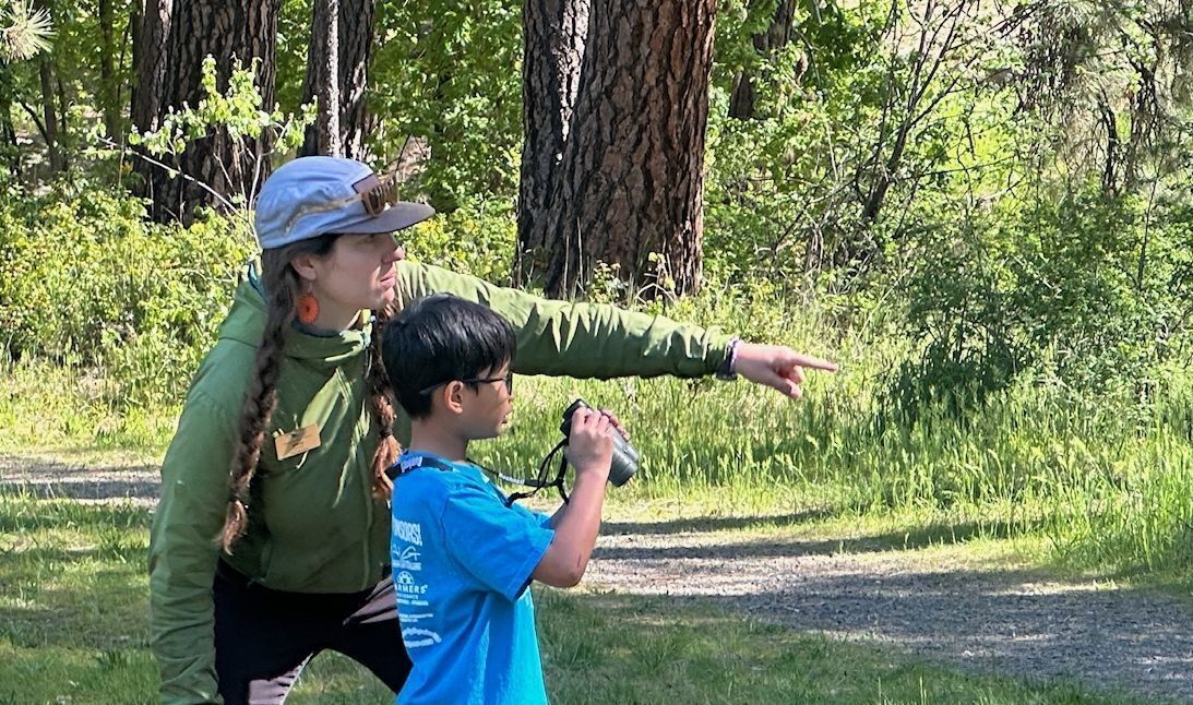 WRI Field Educator, Michaela, helping a student learn how to use binoculars at a Field Day.