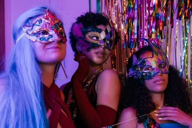 Three women in elaborate Mardi Gras style masks