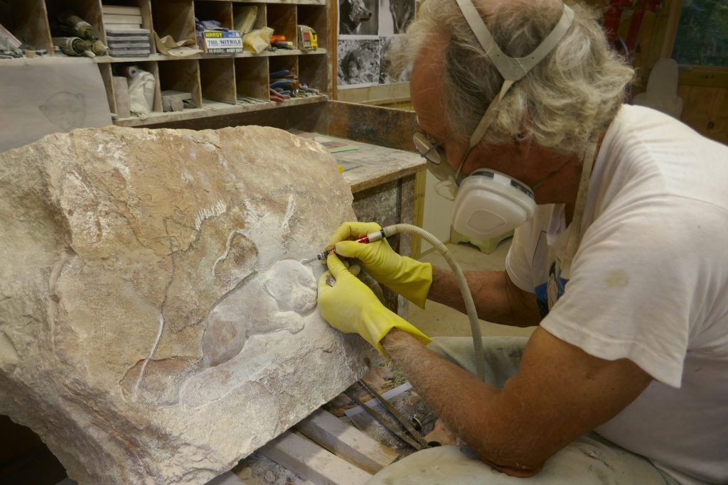 Dale sculpting the puppy with a large mask to protect him from dust