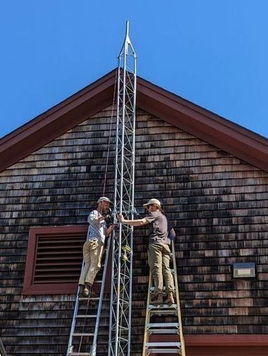 Two men on ladders installing the MOTUS Tower