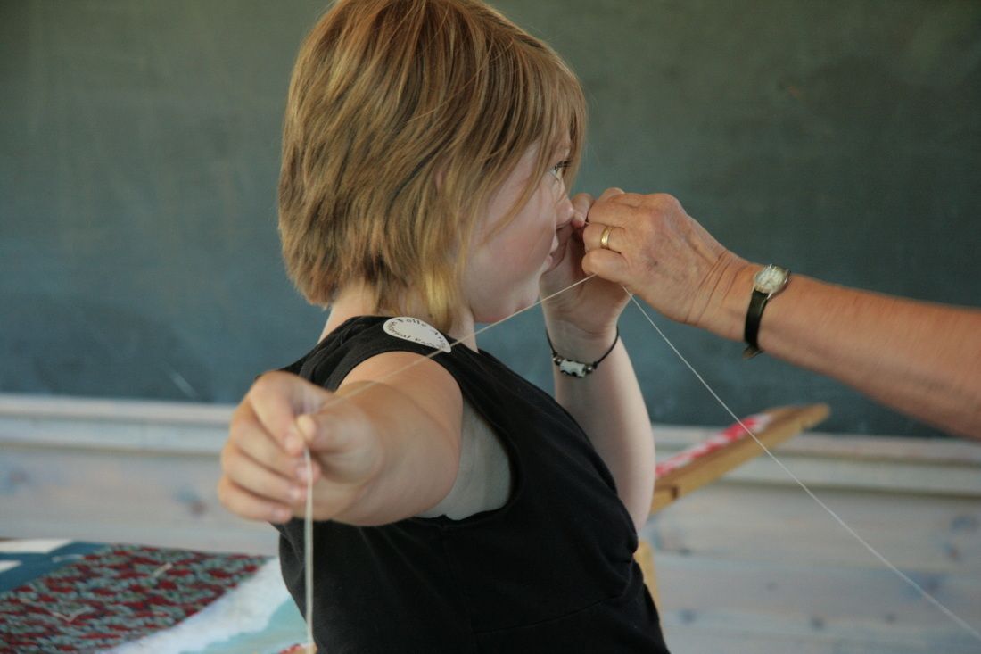 A young person and an adult holding a taut string in a classroom setting.