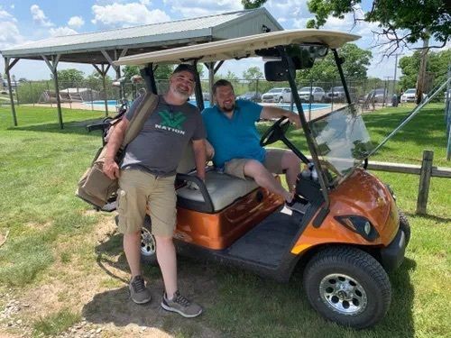 Two men in an orange golf cart.