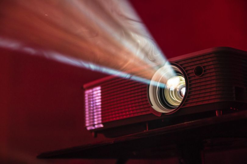 A digital projector turned on and projecting in low light.