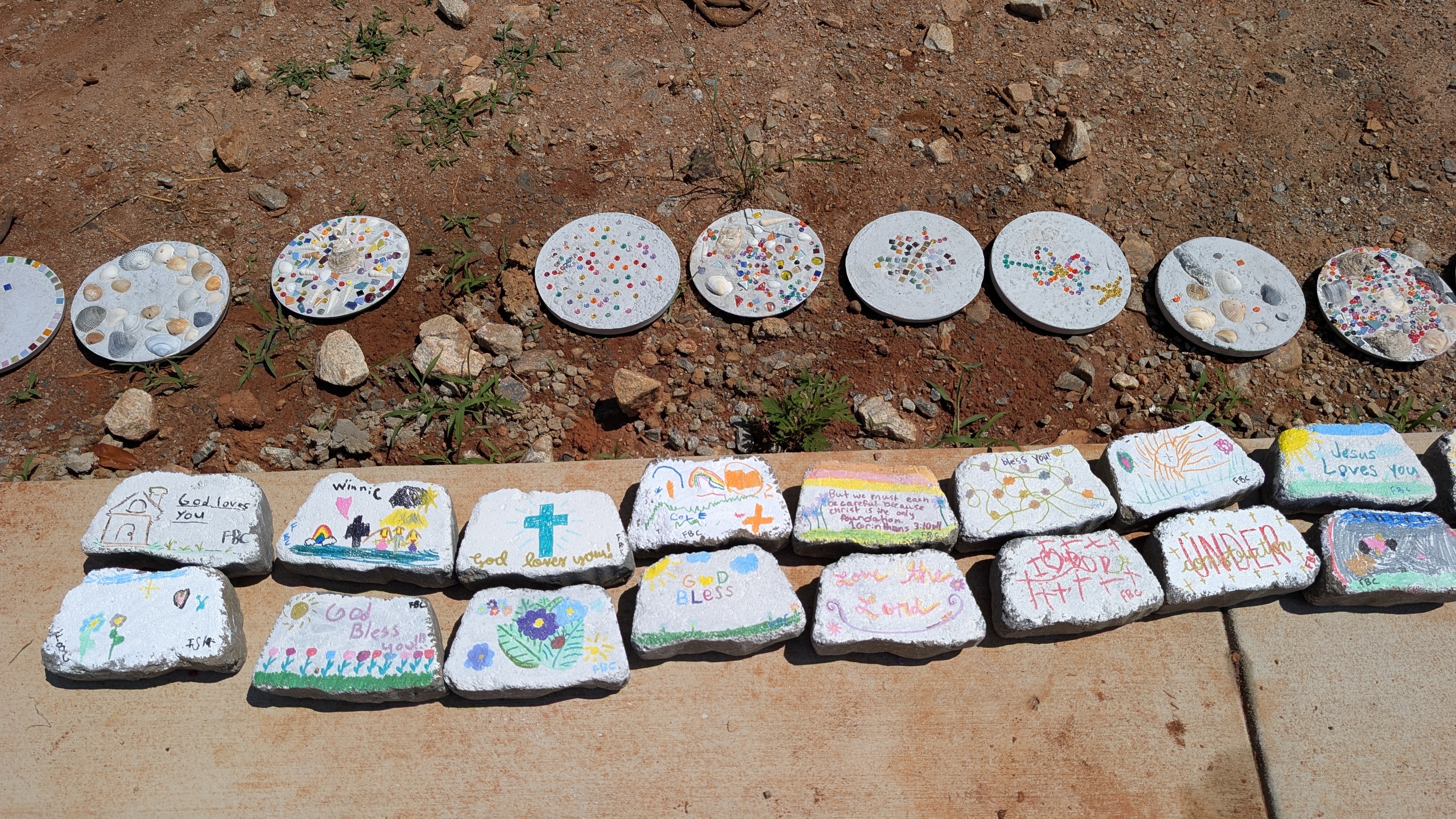 Painted bricks and round stepping stones displayed beside a sidewalk