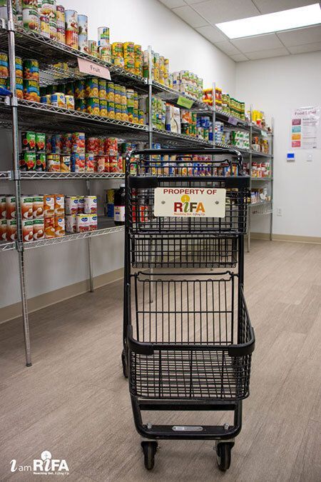 A storage room with shelves full of canned goods and a grocery cart