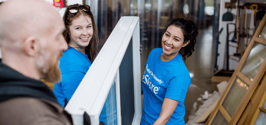 Man hands a window to two ReStore volunteers.