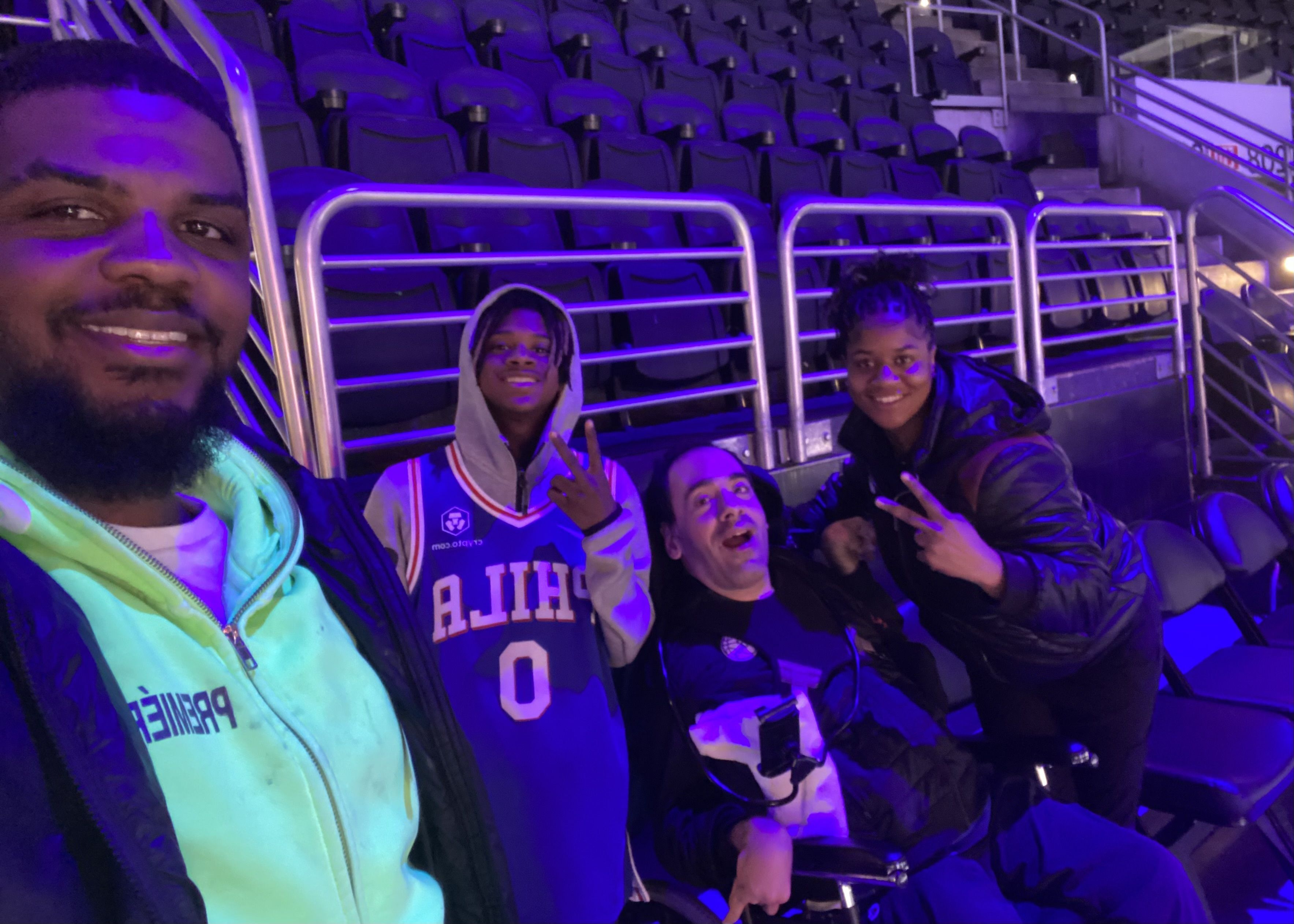 Michael Anderson (center) with his personal care attendant and staff at a 76ers game at Wells Fargo Center
