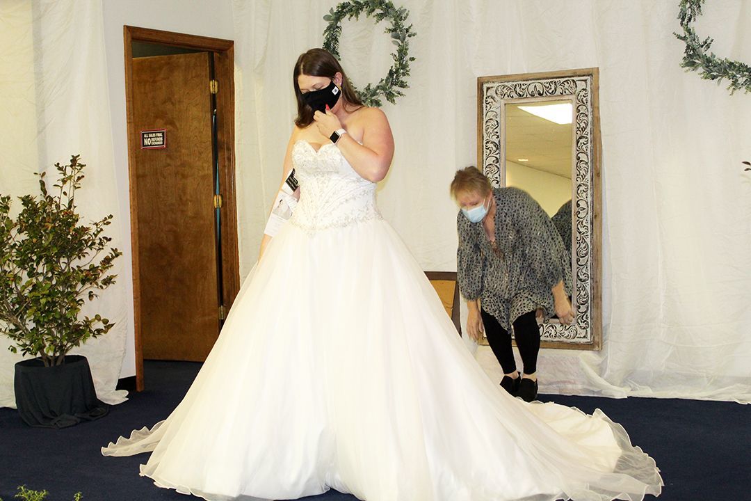 Volunteer Mobilization Coordinator Lisa Brown helps a bride-to-be try on dresses during the bridal dress sale to support BGHNC programs held in February.
