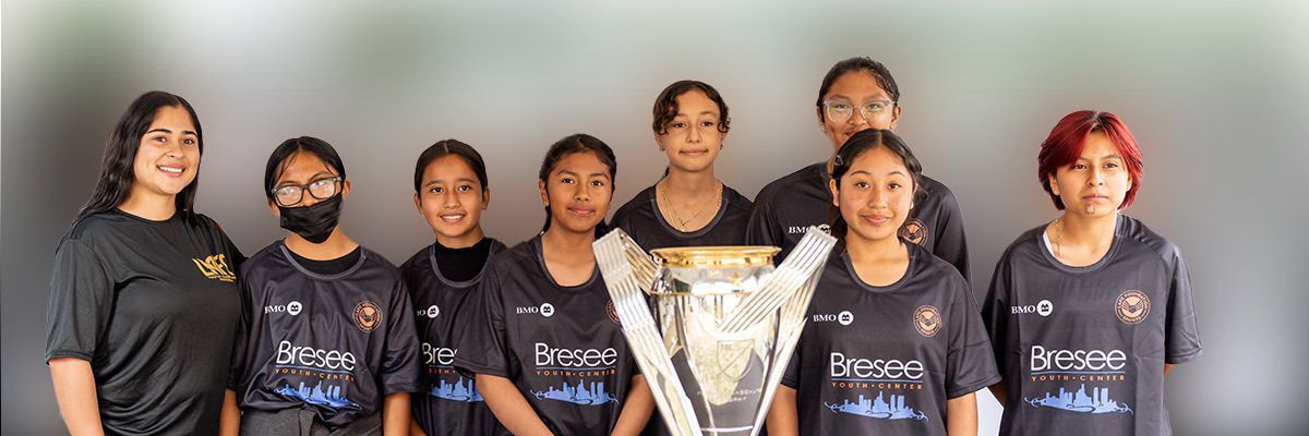 Girls team gather in front of the trophy.