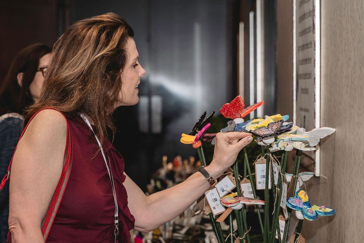 Attendee looking at ceramic student-made butterflies