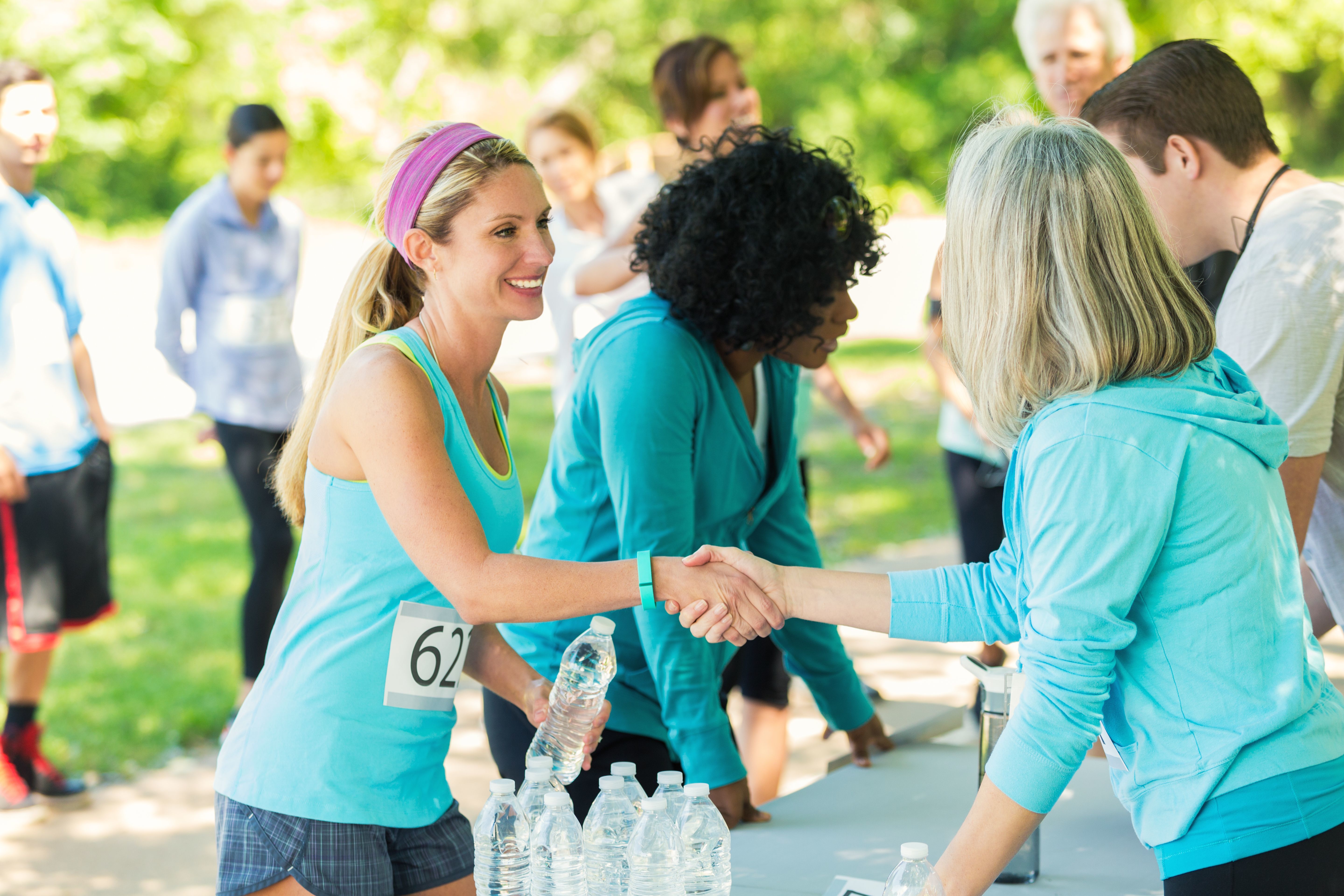 Runners smiling and being greeted by individuals handing out water.