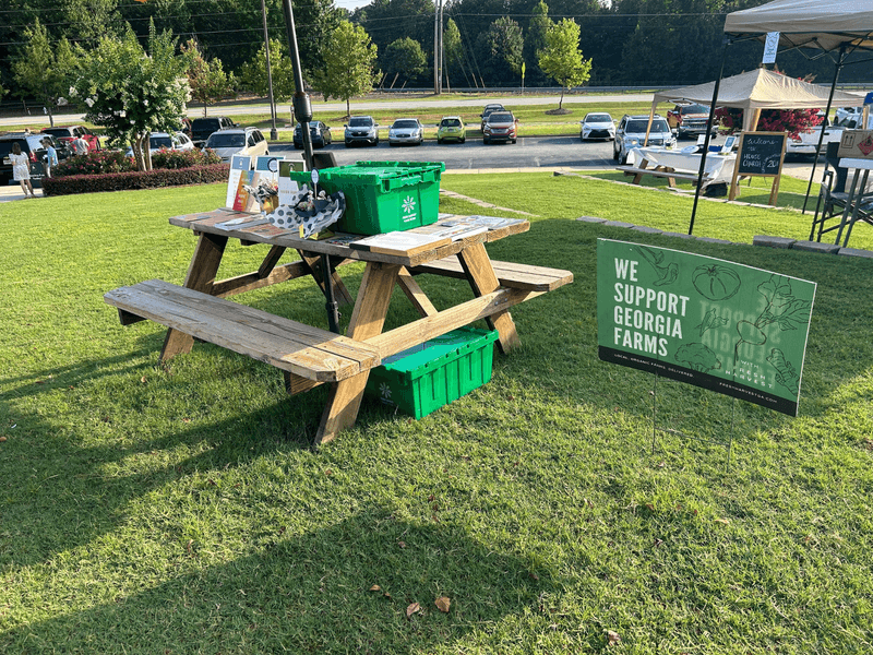 Picnic table with promotional item next to sign that says "We Support Georgia Farms"