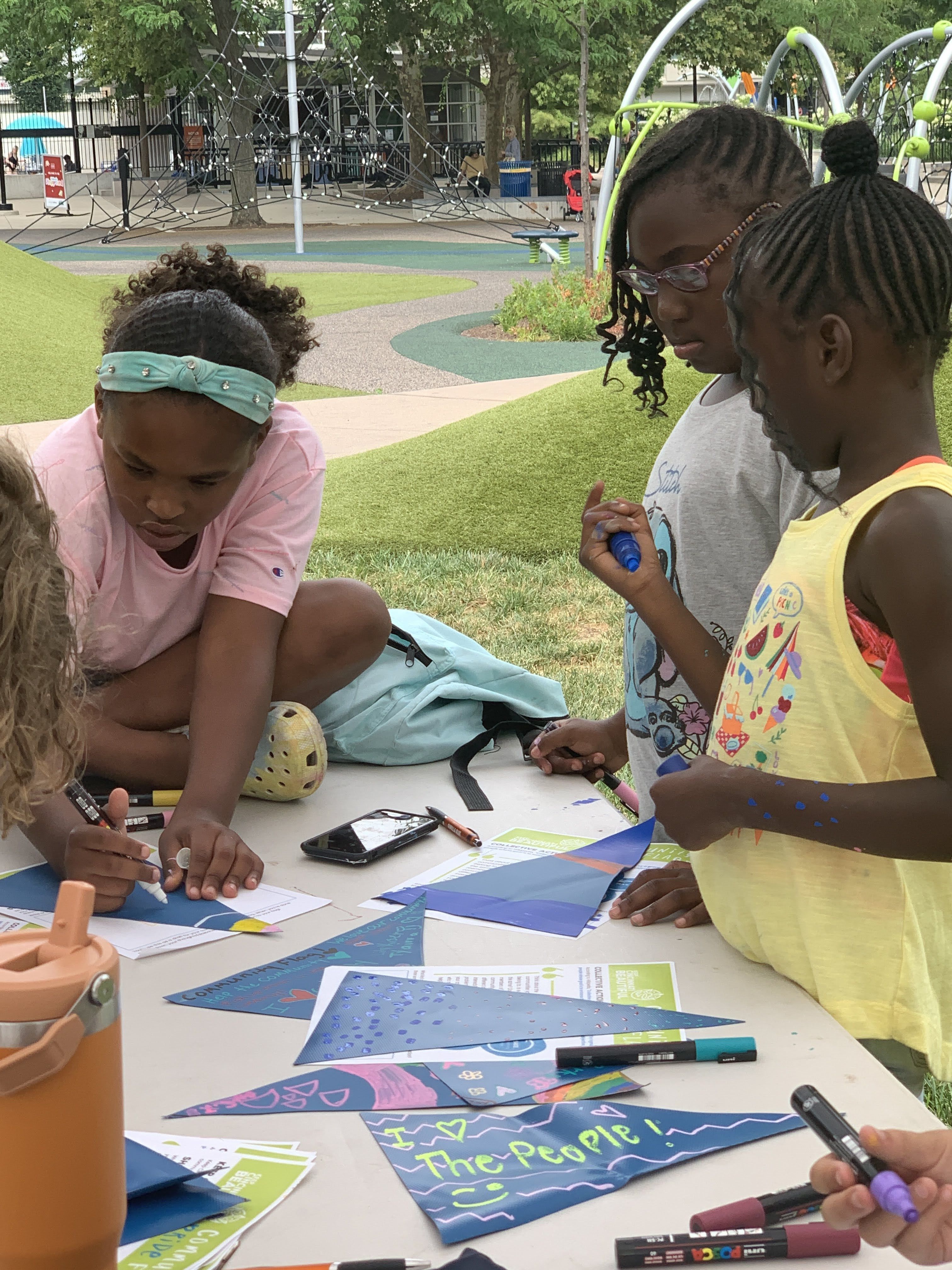 Three children talking and drawing on Community Pride Flags