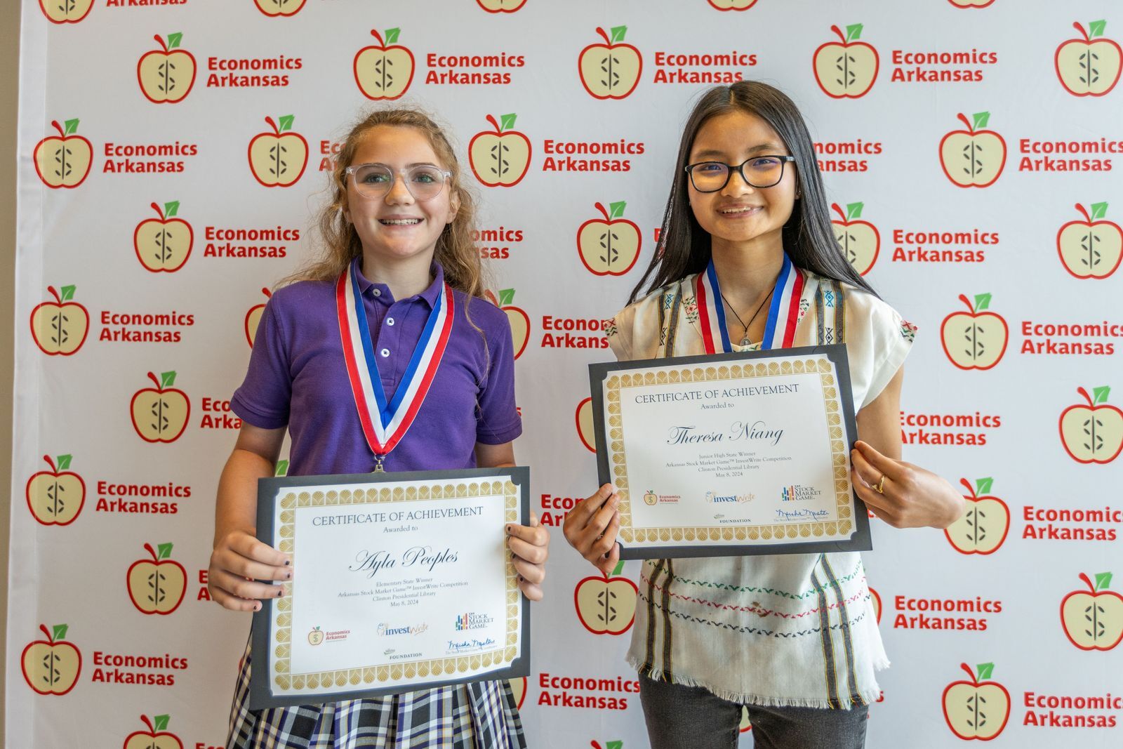 two young girls holding certificates and wearing medallions