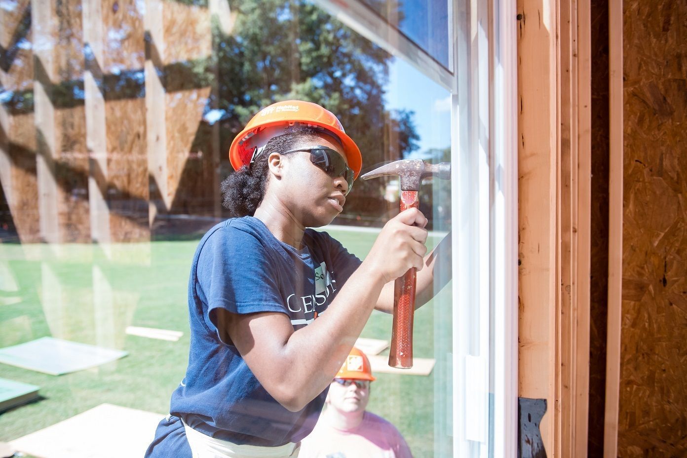 A Clemson University student wears an orange hard hat and hammers a nail on the Homecoming Build on Bowman Field.