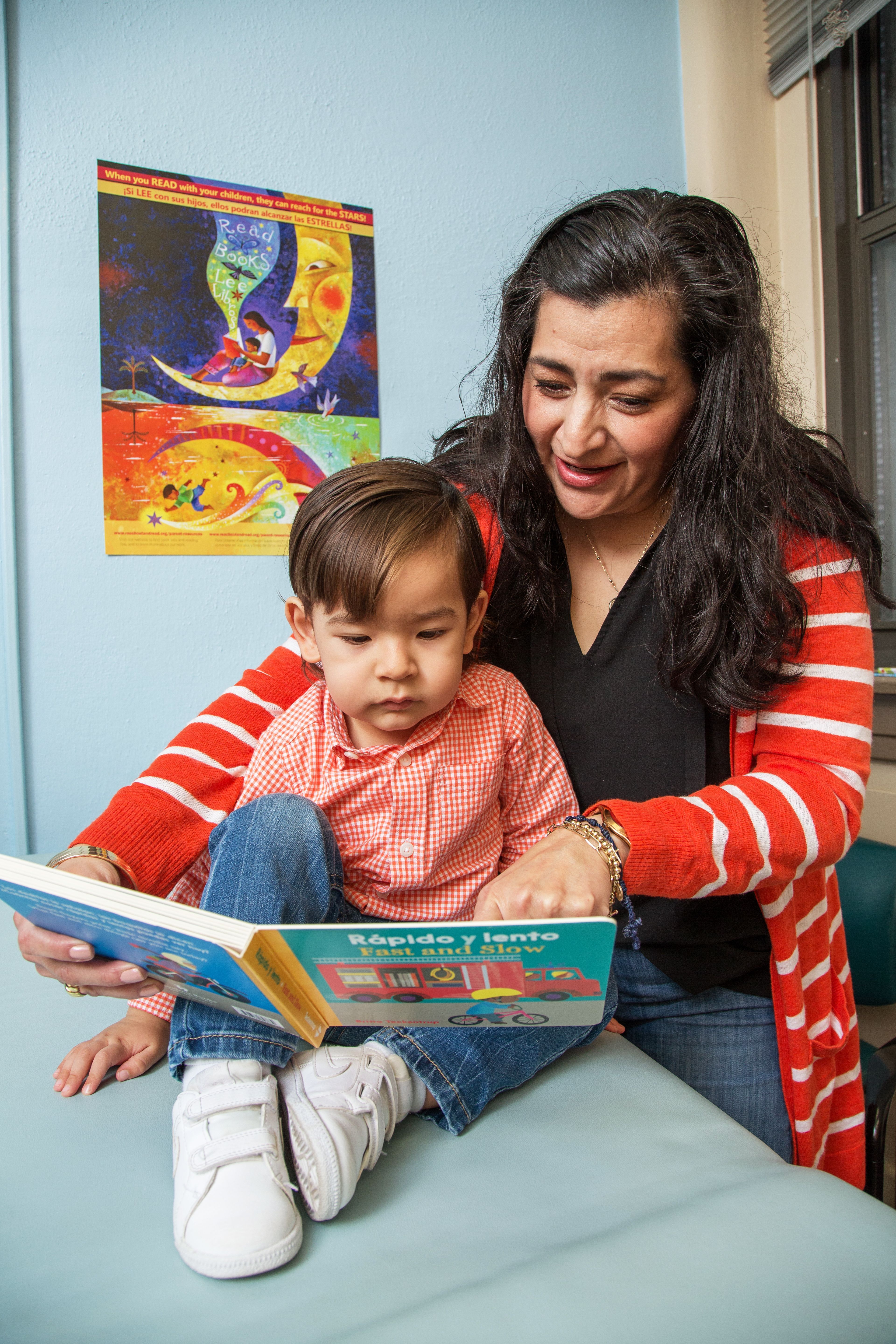 Woman and young child look at book in medical exam room