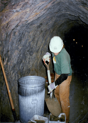 An MCC crew leader in 1996 shovels cement into a 5-gallon bucket.