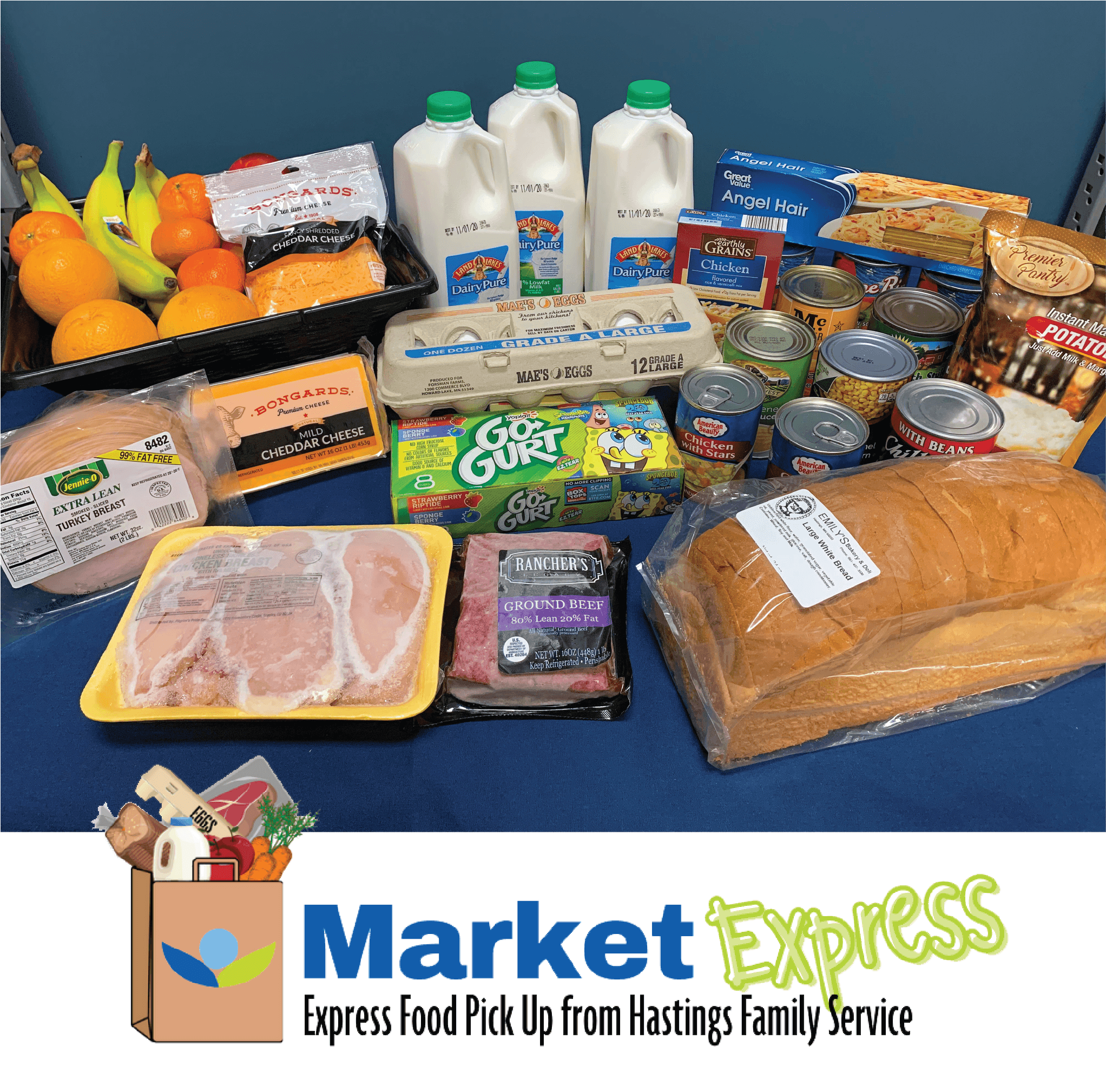 Frozen chicken, meats, bread, 1/2-gallon milks, fresh produce, and canned goods on a tabletop; logo Market Express.