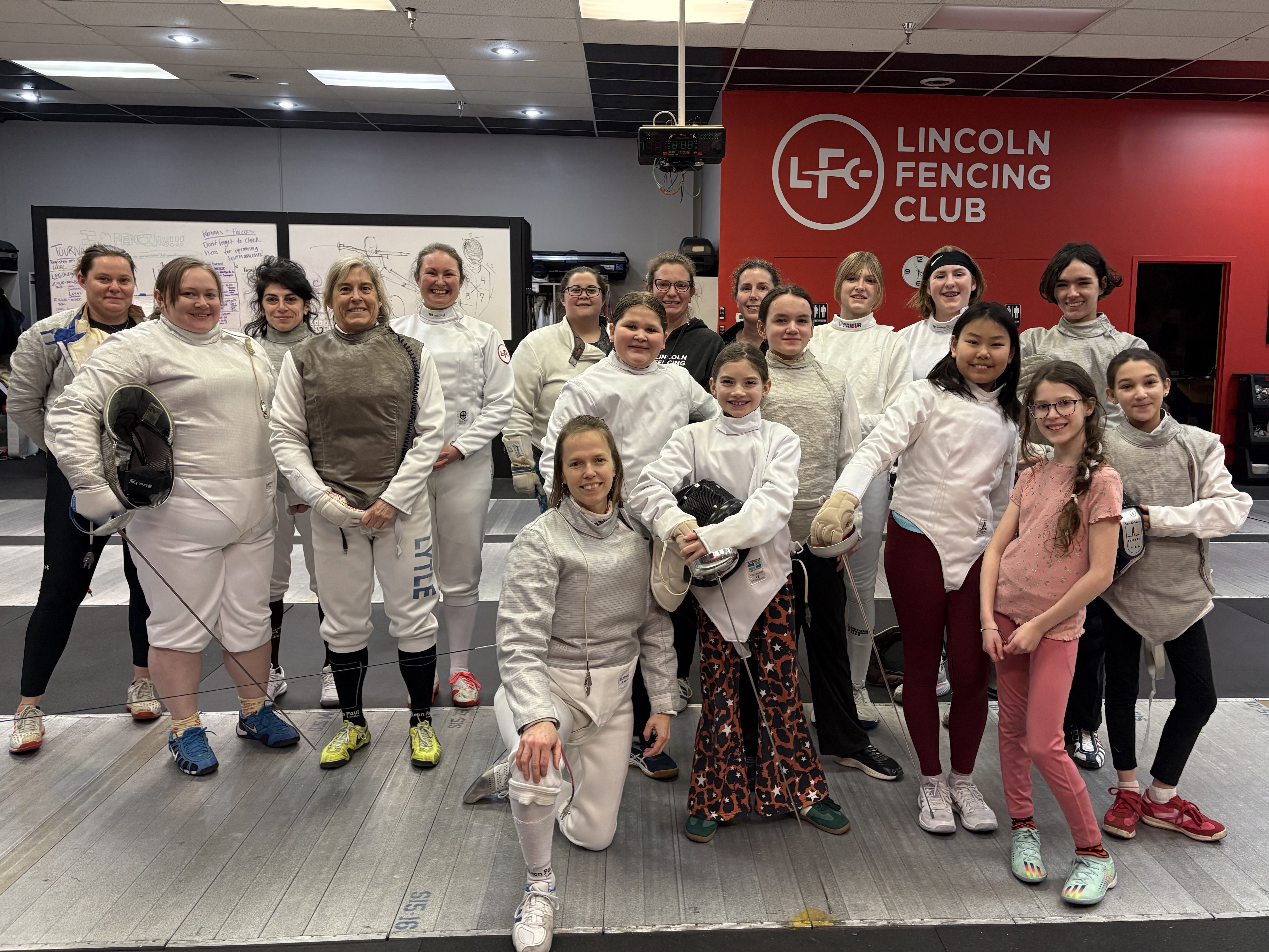 A group of female fencers smile for the camera