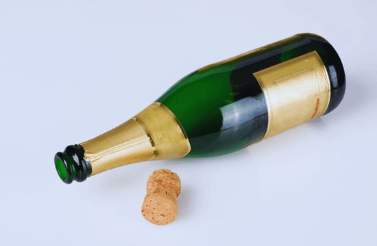 an empty champagne bottle lays on its side next to a cork