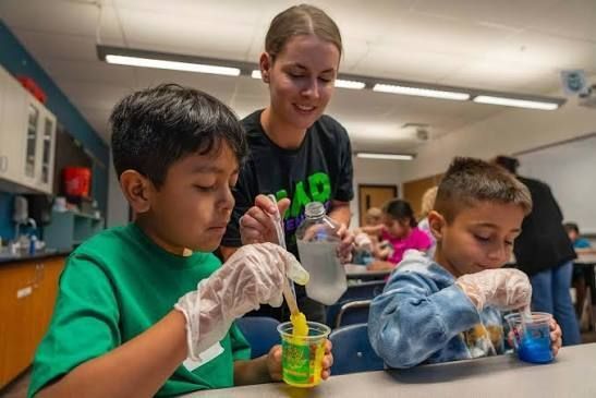 A teacher guides elementary students through a hands-on classroom science activity.