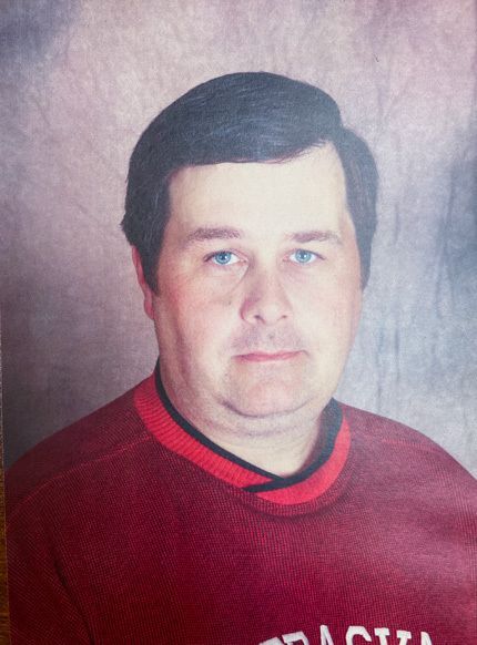Photo of a dark-haired man in a red sweater.