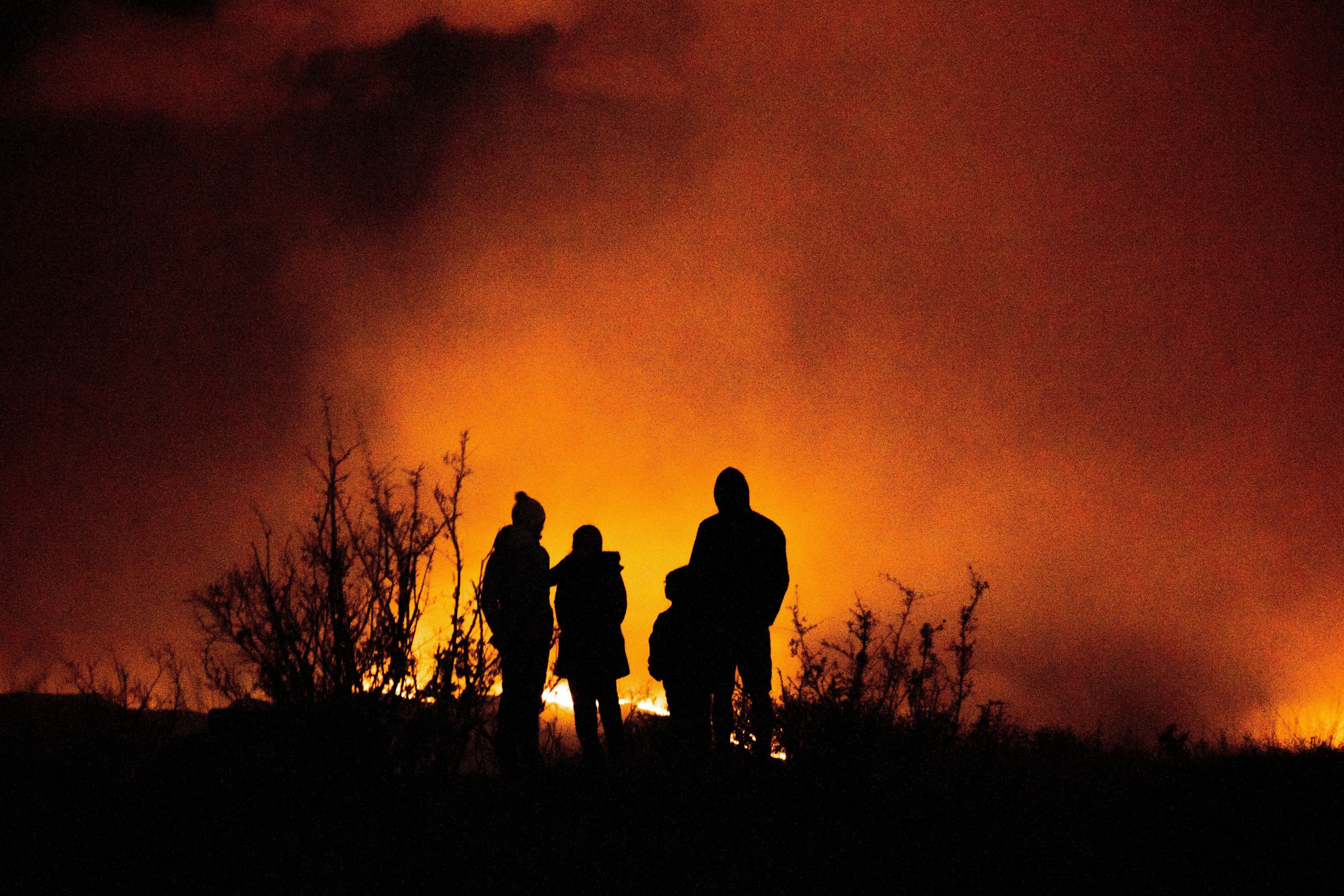 Family standing in front of a wildfire blaze