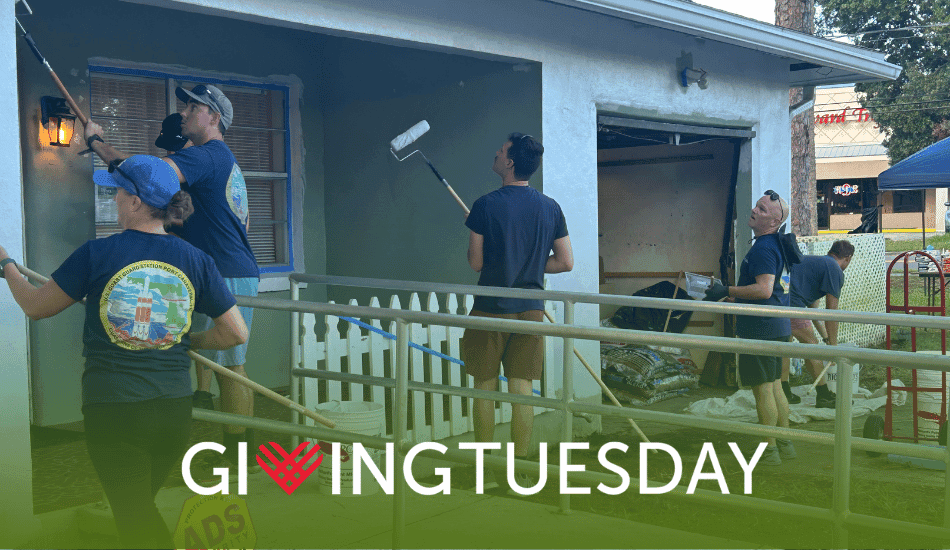 Four smiling volunteers holding paper bags full of groceries for the food pantry.