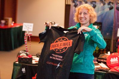 A woman smiles at the camera and holds a PSC Partners shirt